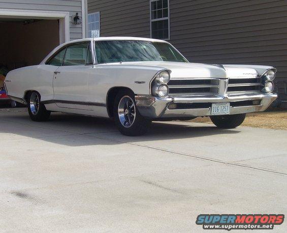 White 1965 Pontiac Catalina with chrome grille and aftermarket wheels parked in a driveway