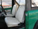 1975 Ford Bronco - The interior of a 1975 Ford Bronco features white vinyl seats and a green exterior.