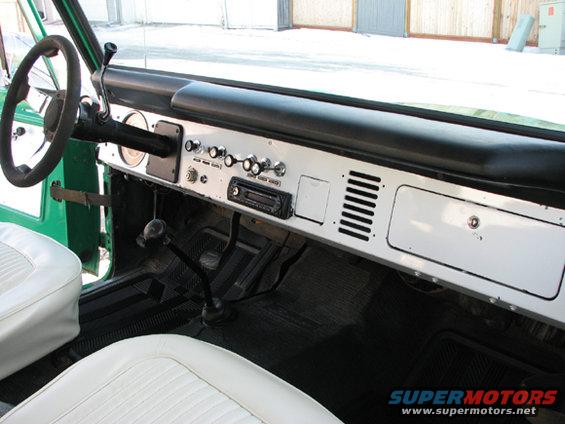 1975 Ford Bronco interior with white seats, black dashboard, and chrome trim