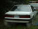 1987 Ford Mustang - A white 1987 Ford Mustang is parked next to a police vehicle.