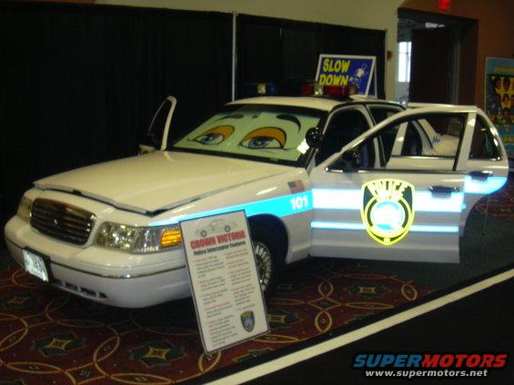 White police car with cartoon eyes on windshield and doors open