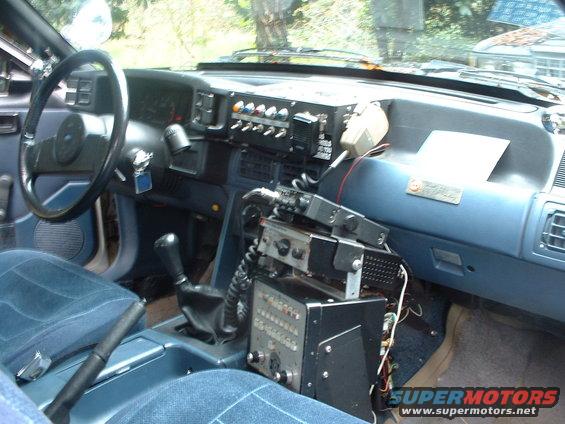 1987 Ford Mustang interior with blue cloth seats, aftermarket radio equipment, and a manual shifter