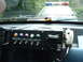 1987 Ford Mustang - Custom switch panel and radio installed in a police car interior, with a light bar visible outside.