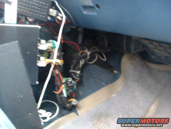 Vehicle interior showing exposed wiring and components under the dashboard