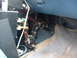 1987 Ford Mustang - Exposed wiring and electronic components are visible beneath the dashboard of a vehicle.