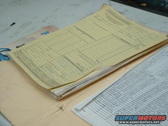 Stack of yellow and white papers with handwritten and printed text