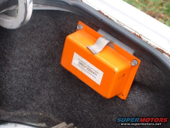 Orange battery jump box mounted in trunk interior