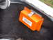 1987 Ford Mustang - An orange battery jump box is mounted inside the trunk of a vehicle.