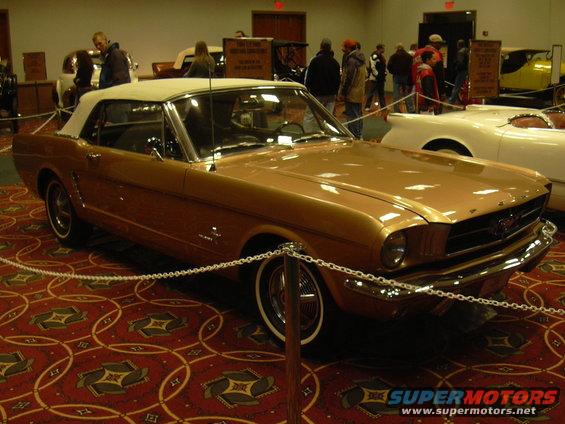 Gold convertible with white top, front end visible. Another white car is next to it