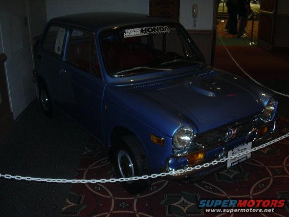 Blue 1970 Honda N600 parked indoors with a chain barrier in front