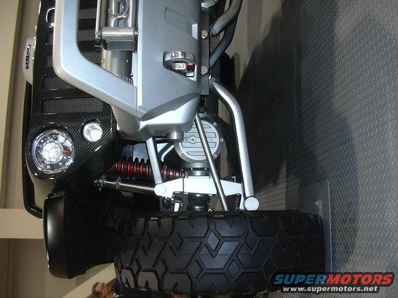 Vehicle front suspension with large tire, carbon fiber grille, and round headlight