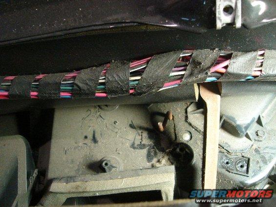 Close-up of a vehicle's interior wiring harness taped with black electrical tape