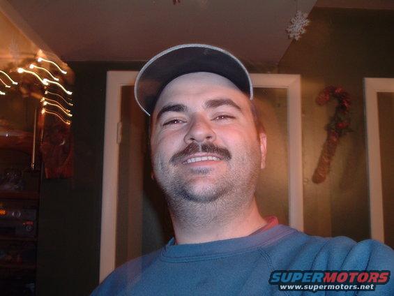 Man wearing a blue sweatshirt and a baseball cap, smiling