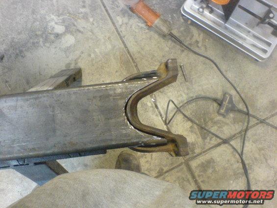 metal frame piece being worked on with grinder and chop saw nearby