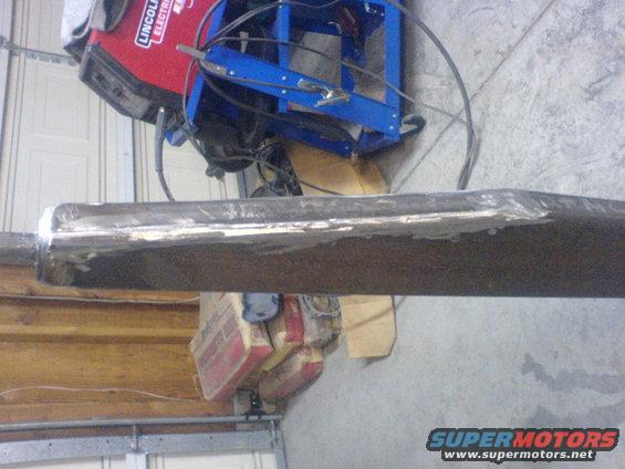 Welding machine and metal beam in garage. Supermotors.net logo visible