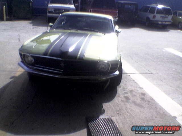 Green 1970 Ford Mustang with black racing stripes, parked outdoors