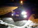 2003 Mercury Marauder - A dark sedan's headlights illuminate a snowy driveway at night.