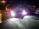 2003 Mercury Marauder - A dark sedan is parked at night, its bright headlights illuminating the ground and casting purple light.