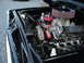1966 Ford F-100 - The engine bay of a black vehicle showcases a powerful Ford V8 engine with performance upgrades.