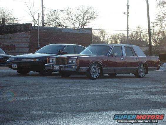 Maroon Lincoln Town Car and black sedan parked on asphalt