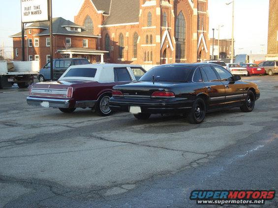 Black 1992 Ford Crown Victoria parked on asphalt, rear view. Another car is parked to its left