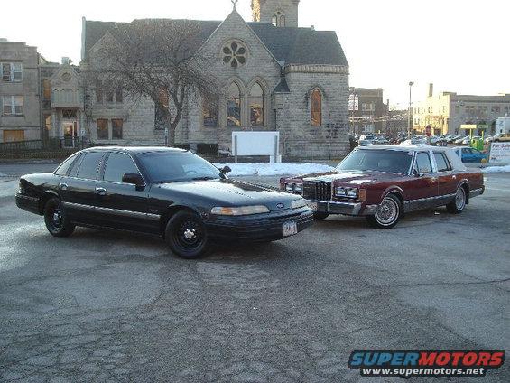 black sedan and maroon sedan parked next to each other in front of a building
