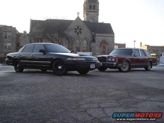 Black 1992 Ford Crown Victoria parked next to a maroon Lincoln Town Car, front 3/4 view