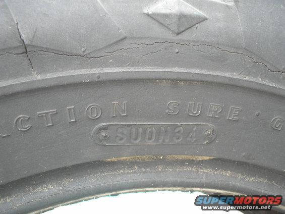 Close-up of tire tread with text 'TRACTION SURE' and 'SUON34'