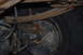1996 Ford Bronco - Close-up view of a vehicle's rear axle and suspension system, revealing rusty components and a brake drum.