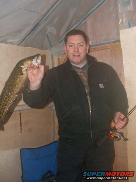 man holding a large fish, fishing rod in hand