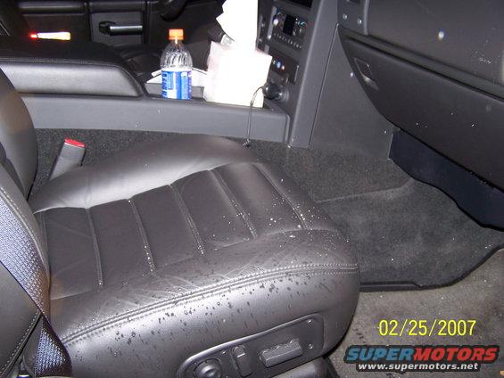 Black leather car seat with water spots, center console with bottle and tissues, date stamp 02/25/2007
