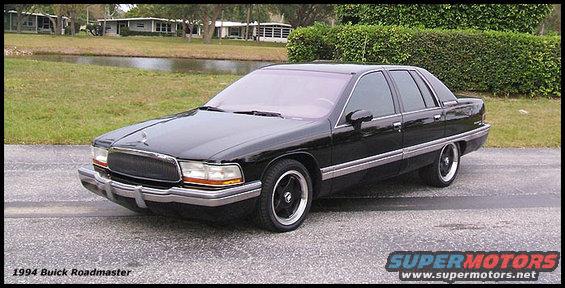 Black 1994 Buick Roadmaster parked on asphalt with a pond and houses in background
