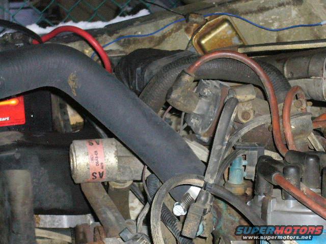 1979 Ford Bronco engine compartment with hoses, wires, and a battery