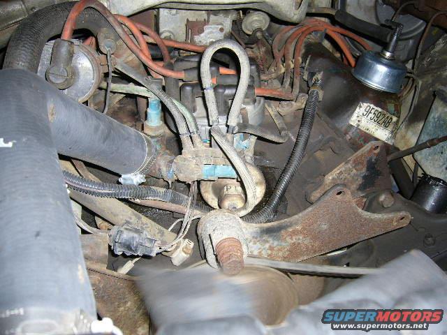 engine bay with hoses, wires, and a label reading 9F592AB