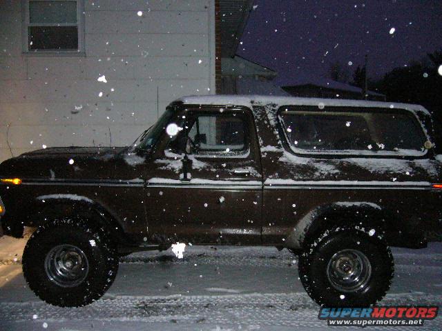 1978 Ford Bronco parked outside in falling snow, side view