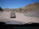 1996 Ford Bronco - Two Jeeps navigate a rough, rocky terrain under a clear blue sky.