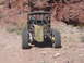 1996 Ford Bronco - A modified off-road vehicle is parked on a dirt path with a rocky hillside in the background.
