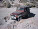 1996 Ford Bronco - Jeep Wrangler TJ tackling an off-road trail with rocky obstacles.