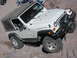 1996 Ford Bronco - A white Jeep Wrangler Rubicon navigates a challenging rocky trail.