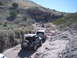 1996 Ford Bronco - Multiple off-road vehicles traverse a challenging rocky trail in a desert landscape.