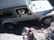 1996 Ford Bronco - A silver Jeep Wrangler is shown maneuvering through a challenging rocky path, with the driver looking out the window.