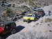 1996 Ford Bronco - A group of off-road vehicles navigate a dusty, rocky trail in a desert landscape.