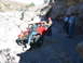 1996 Ford Bronco - A red Jeep Wrangler maneuvers through a challenging rocky path, observed by several onlookers.
