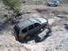 1996 Ford Bronco - Two Jeeps tackle a challenging off-road course in a desert landscape.