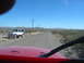 1996 Ford Bronco - View from inside a red vehicle looking out at a white Jeep parked on a dusty road with mountains in the distance.