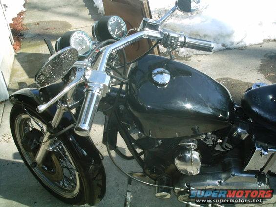 Black motorcycle fuel tank and chrome handlebars with gauges visible