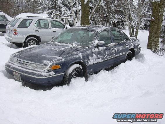 Dark blue 1996 Ford Crown Victoria stuck in deep snow, front 3/4 view