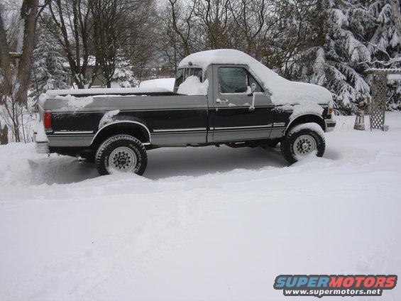 Pickup truck covered in snow, parked outside
