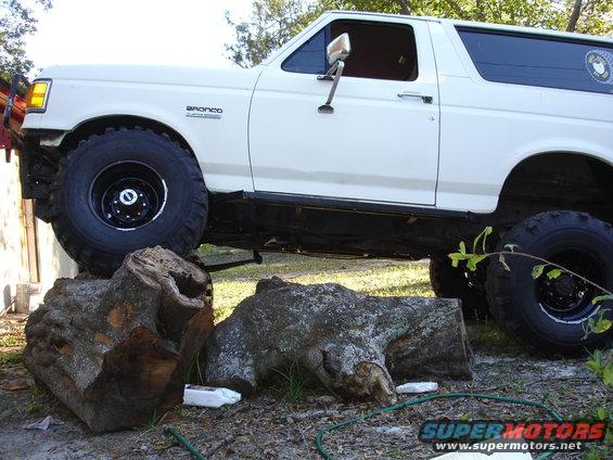 1989 Ford Bronco with large tires, partially obscured by logs