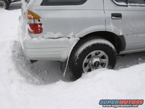 Silver SUV's rear tire buried in snow, showing a portion of the taillight and bumper